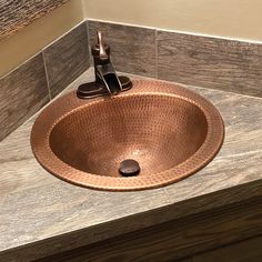 a copper sink in the corner of a bathroom