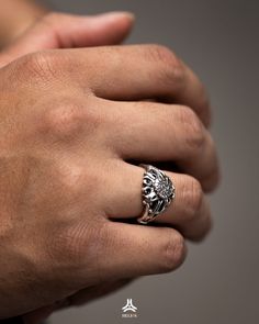 a man's hand wearing a silver ring with a lion head on it,