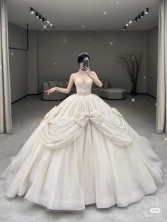 a woman in a ball gown is talking on her cell phone while standing in an empty room