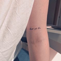 a person with a tattoo on their arm that says, let it be written in cursive writing