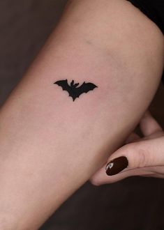 a woman's arm with a small bat tattoo on the left side of her body