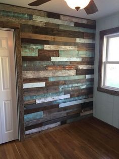 an empty room with wood planks on the wall and a ceiling fan in it