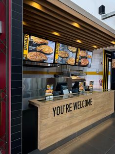 a restaurant counter with menus on the wall behind it and a sign that says you're welcome