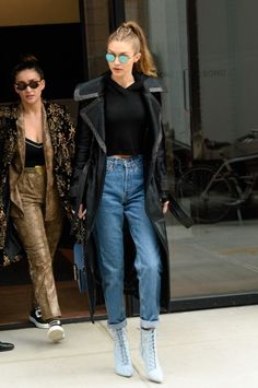 two women walking down the street in front of a building with their hands in their pockets