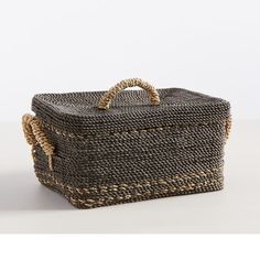 a woven storage basket with handles on the top and bottom, sitting on a white surface