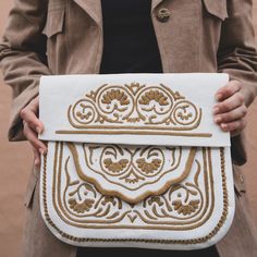 In Morocco, hand embroidery serves as a thread connecting generations, with mothers teaching daughters the craft. Embroidered designs can be found on various items in the souks—from handkerchiefs to poufs and bags—and the designs differ from city to city. This satchel, the perfect size for books, has proven itself a versatile companion for any adventure. 10" tall, 11" wide Detachable shoulder strap Embroidered leather Traditional White Travel Bag, Embroidered Cream Clutch Bag, Traditional White Shoulder Bag For Travel, White Rectangular Bag With Machine Embroidery, White Rectangular Bags With Machine Embroidery, Artisan Embroidered Pouch Bag, Traditional Handmade Cream Bags, Embroidered Cream Shoulder Bag As Gift, Traditional White Embroidered Shoulder Bag