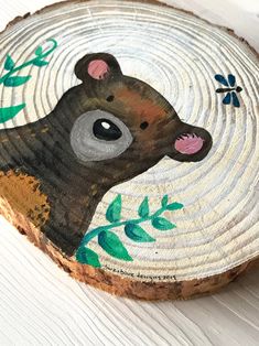 a piece of wood with a bear painted on it's face and some leaves