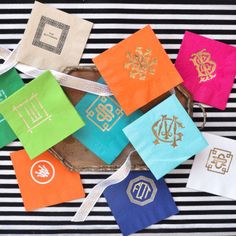 colorful napkins with monogrammed designs on them sitting on a striped tablecloth