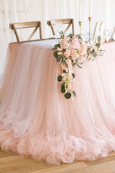 a table with pink tulle and flowers on it, surrounded by candlesticks