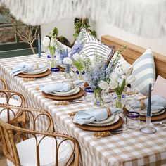 the table is set with blue and white plates, napkins, and vases