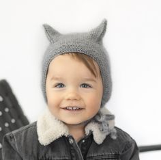 a little boy wearing a gray knitted hat with horns on it's head