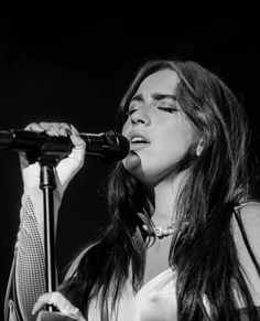 a woman with long hair singing into a microphone