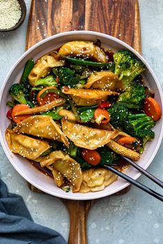 a white bowl filled with broccoli, carrots and noodles