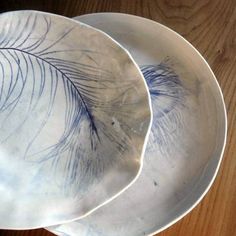 two blue and white plates sitting on top of a wooden table next to each other