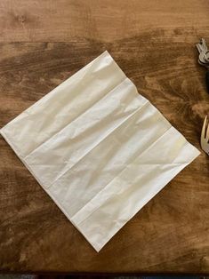 a napkin and some silverware are on a wooden table next to a pair of scissors