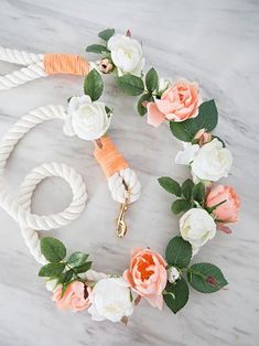 a white rope with flowers on it and a dog leash attached to it, sitting on a marble surface