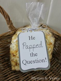 a bag of popcorn sitting on top of a wicker basket next to a sign that says he popped the question