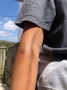 a person with a small tattoo on their left arm and the other arm behind him