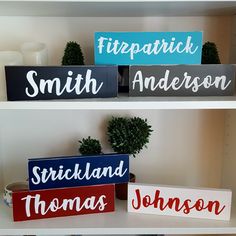 three wooden signs that are on top of a book shelf, each with their own name