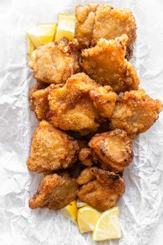 fried chicken with lemon wedges and ketchup on white parchment paper, ready to be eaten