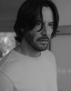 a black and white photo of a man with long hair wearing a t - shirt