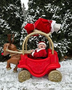 a baby in a red toy car with santa claus on it's head and reindeer behind him