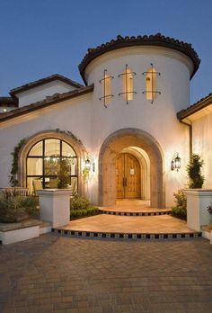 a large white house with lots of windows and lights on it's front entrance