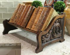 an old wooden book stand with many books on it's sides and two vases in the background