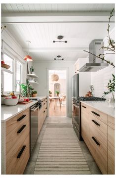 a long narrow kitchen with wooden cabinets and stainless steel appliances, along with an area rug on the floor