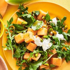 a yellow plate topped with watermelon and feta cheese next to a bowl of peas