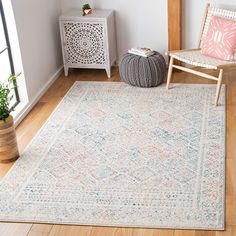 a living room area with a chair and rug on the hardwood floor, next to a window