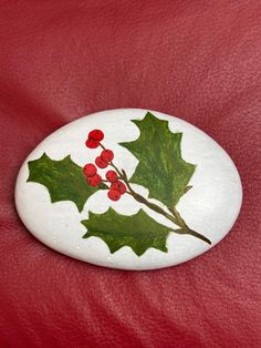 Christmas holly and leaves painted with acrylic. The product can be used as outdoor decor as it is coated with a water-resistant spray. May begin to fade if kept in direct sunlight for a long period of time. Winter Rock Painting Ideas, Christmas Rocks, Paint Rock, Rock Painting Art, Hand Painted Rocks, Christmas Holly, Painted Rock, Staten Island