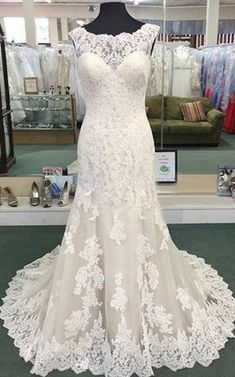 a white wedding dress on display in a store with other dresses and accessories behind it