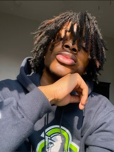 a young man with dreadlocks wearing a hoodie and looking at the camera