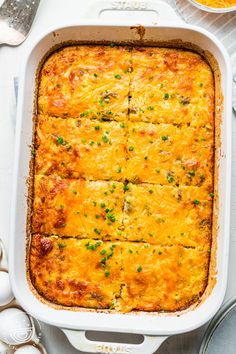 a casserole dish with meat and cheese in it on a white table next to utensils