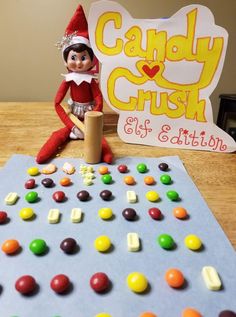 an elf sitting on top of a table next to a candy crush board