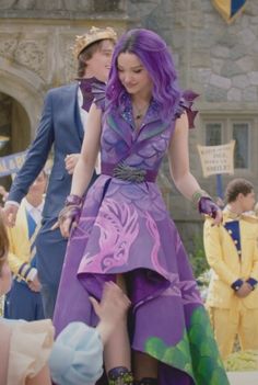 a woman in a purple dress is dancing with other people