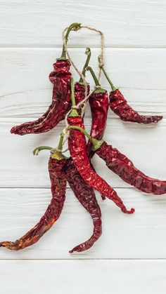 red peppers hanging from strings on white wood