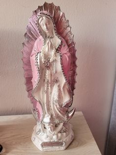 a pink and white figurine on a wooden table next to a cell phone