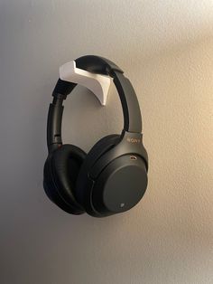 a pair of headphones hanging on the wall in front of a white wall with a black earphone attached to it