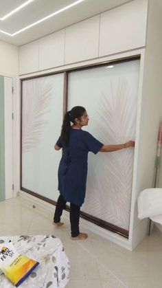 a woman standing next to a sliding glass door in a room with white walls and tile flooring