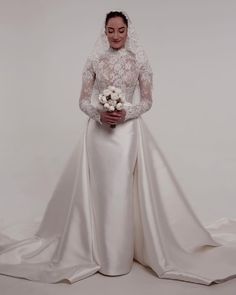 a woman in a wedding dress holding a bouquet of flowers and posing for the camera