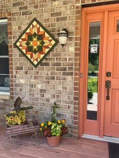 two flower pots sitting on the front porch next to an orange door and brick wall