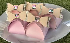 there are many pink and gold bow decorations on the white plate with green grass in the background