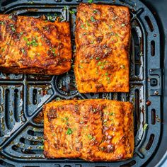 four square pieces of cooked food on top of an air fryer pan with green garnishes