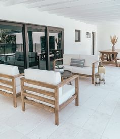 a living room filled with white furniture and lots of glass doors leading to an outside patio