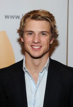 a young man in a suit smiling for the camera