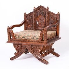 an ornate carved wooden chair and ottoman with floral upholstered fabric on the seat