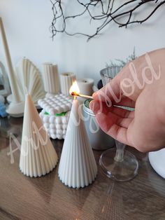 a person lighting a candle on top of a wooden table next to other small objects