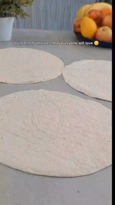 three uncooked tortillas sitting on top of a table next to fruit